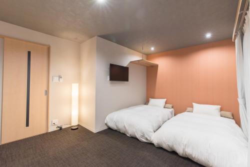 a bedroom with two beds and a tv on the wall at Stay SAKURA Kyoto Higashiyama Shirakawa in Kyoto