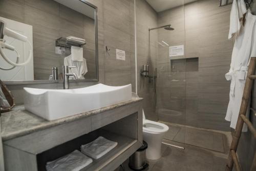 uma casa de banho com um lavatório e um chuveiro com um WC. em White Boutique Hotel and Residences em Sihanoukville