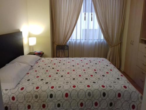 Un dormitorio con una cama grande con flores rojas. en Cerca a Mitad del Mundo en Quito