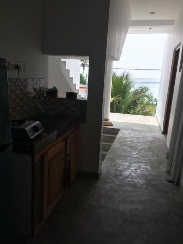 a kitchen with a large window and a view of the ocean at Blue Corals Beach Bungalow in Madihe East