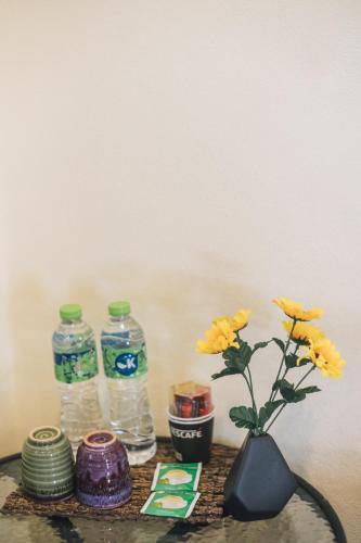 a table with two bottles of water and a vase with flowers at Kristi House in Chiang Mai