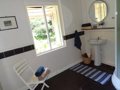La salle de bains est pourvue d'une chaise, d'un lavabo et d'une fenêtre. dans l'établissement Strathisla Tea Estate Bungalow, à Matale