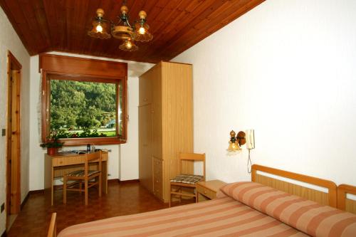 a bedroom with a bed and a desk and a window at Hotel Edelweiss in Villeneuve