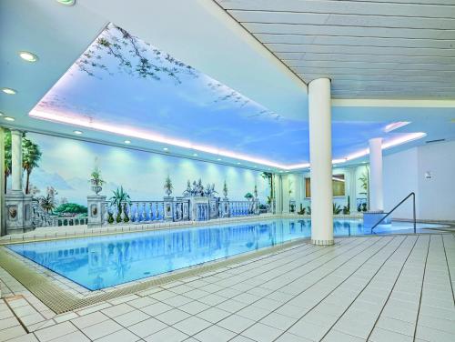 a large swimming pool in a building with a large window at Berghotel Jägerhof ****S in Isny im Allgäu