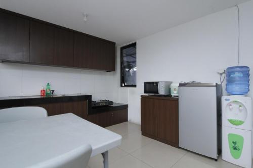 a kitchen with a white table and a refrigerator at RedDoorz Plus near Plaza Indonesia in Jakarta