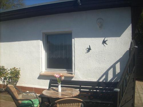 eine Terrasse mit einem Tisch, Stühlen und Vögeln an einer Wand in der Unterkunft Bungalow Bansin in Bansin