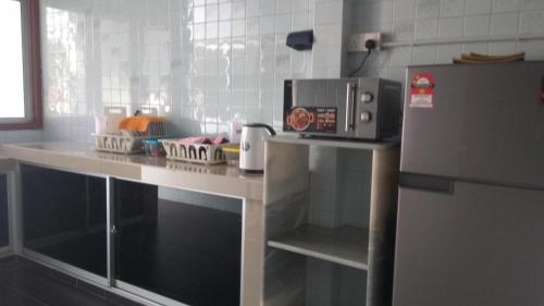 a kitchen with a counter with a microwave and a refrigerator at Gopeng TownHouse in Gopeng