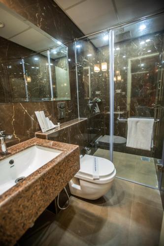 a bathroom with a tub and a toilet and a shower at Hotel Paramos Inn in Bengaluru