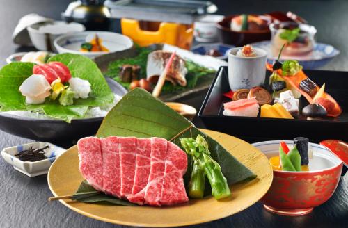 une table recouverte de plaques alimentaires avec de la viande et des légumes dans l'établissement Honjin Hiranoya Kachoan, à Takayama