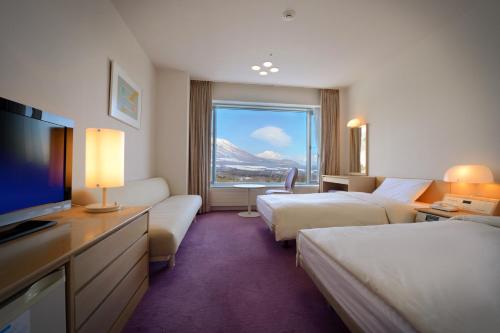 a hotel room with two beds and a flat screen tv at Shizukuishi Prince Hotel in Shizukuishi