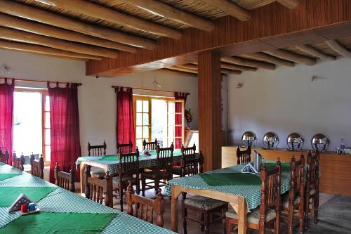 a dining room with tables and chairs and windows at Tiger Camp Nubra in Nubra
