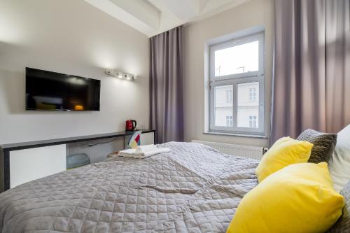 a bedroom with a bed with a television on the wall at SAVOY Mariacka Apartments in Katowice