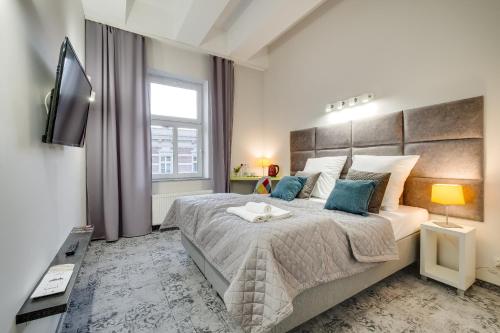a bedroom with a large bed and a television at SAVOY Mariacka Apartments in Katowice