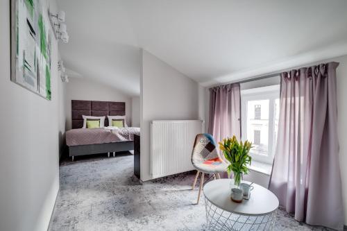 a bedroom with a bed and a table and a chair at SAVOY Mariacka Apartments in Katowice