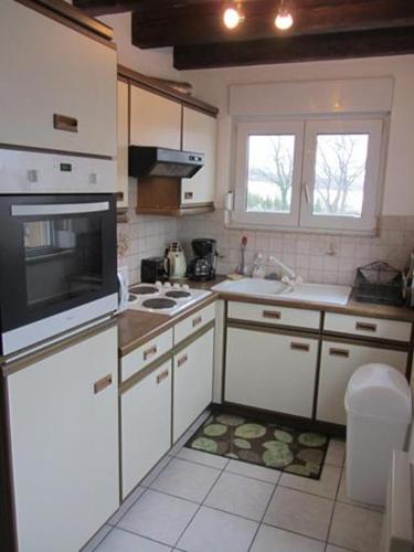 a kitchen with white cabinets and a stove top oven at Gite de Grandvillars in Grandvillars