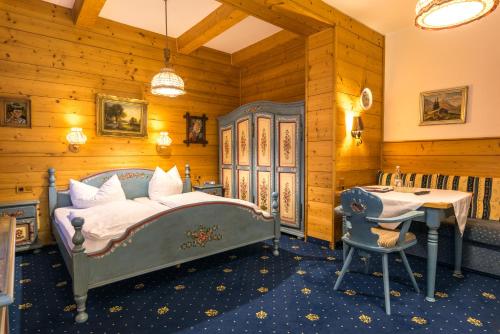 a bedroom with a bed and a desk and a table at Hotel garni Almenrausch und Edelweiss in Garmisch-Partenkirchen