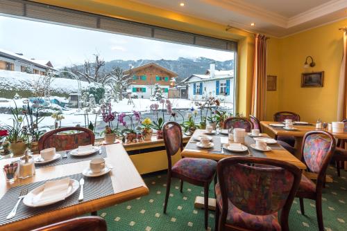 a restaurant with tables and chairs and a large window at Hotel garni Almenrausch und Edelweiss in Garmisch-Partenkirchen