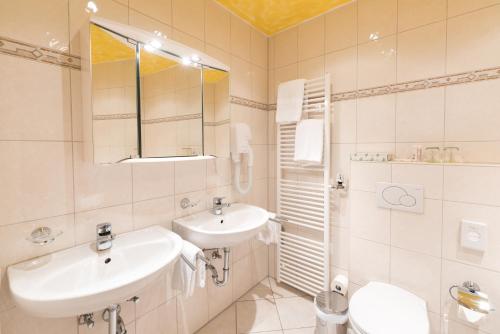 a white bathroom with a sink and a mirror at Hotel garni Almenrausch und Edelweiss in Garmisch-Partenkirchen