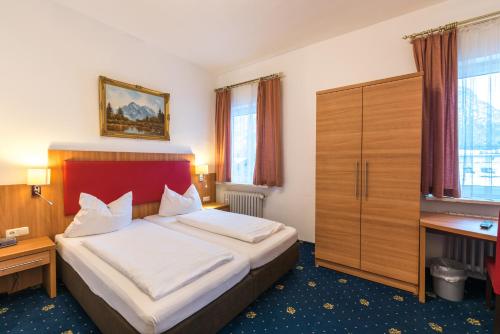 a hotel room with a bed and a desk at Hotel garni Almenrausch und Edelweiss in Garmisch-Partenkirchen