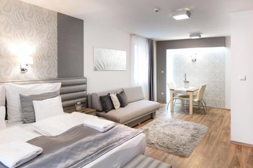 um quarto com uma cama, um sofá e uma mesa em Főtér Rezidencia em Gyor