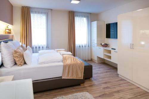 a bedroom with a bed with white furniture and windows at Főtér Rezidencia 2 in Győr