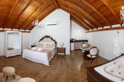 een slaapkamer met een bed en een bad bij Chalés Pomerode in Pomerode