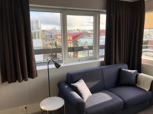 a living room with a blue couch and a window at Svala Apartments by Heimaleiga in Reykjavík