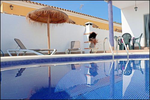 einen Pool mit Sonnenschirm und Stühlen in der Unterkunft Chalet Muelle Pesquero 66 in Conil de la Frontera