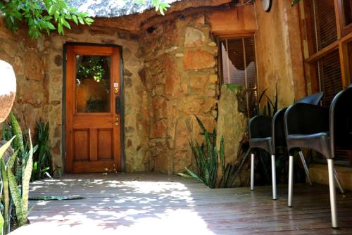 a stone house with a wooden door and chairs outside at Sherewood Lodge in Pretoria