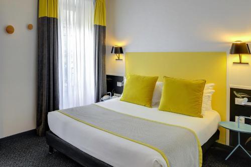 a hotel room with a large bed with yellow walls at Hotel George - Astotel in Paris