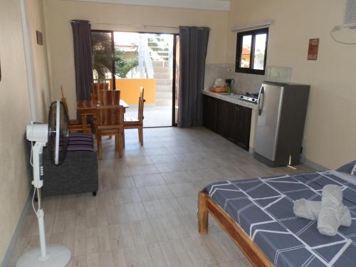 a bedroom with a bed and a kitchen with a refrigerator at The Blue Pagong in Puerto Galera