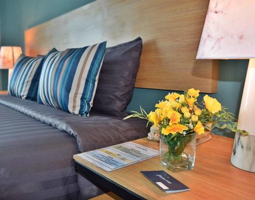 a vase of flowers on a table next to a couch at Vogue Pattaya Hotel in Pattaya Central