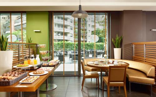 a restaurant with tables and chairs and a large window at UNA Hotels The One Milano Hotel & Residence in San Donato Milanese