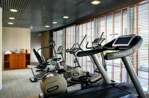 a gym with several cardio machines in front of a large window at UNA Hotels The One Milano Hotel & Residence in San Donato Milanese