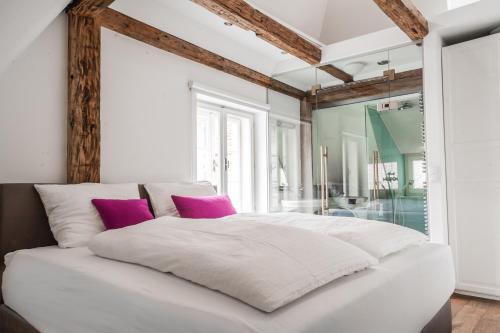 a bedroom with a white bed with purple pillows at DAREBELL – Designerapartments Sporgasse in Graz