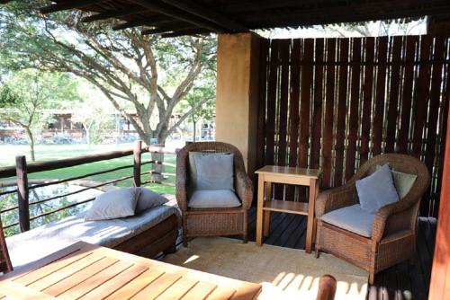 a porch with two chairs and a bed and a table at Sherewood Lodge in Pretoria
