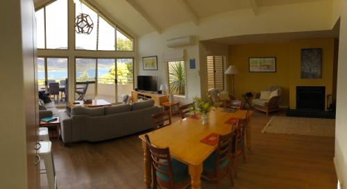 a living room with a couch and a table and chairs at Freycinet Beach House in Coles Bay