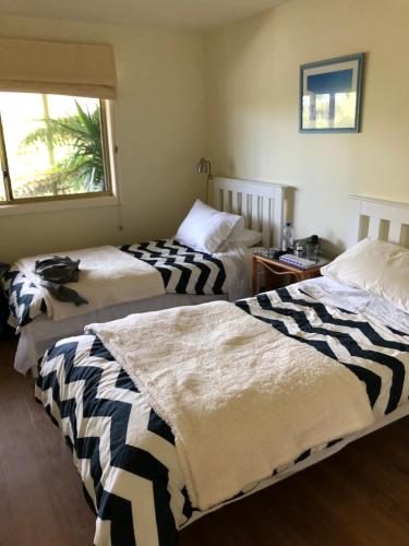 two beds in a room with a window at Freycinet Beach House in Coles Bay