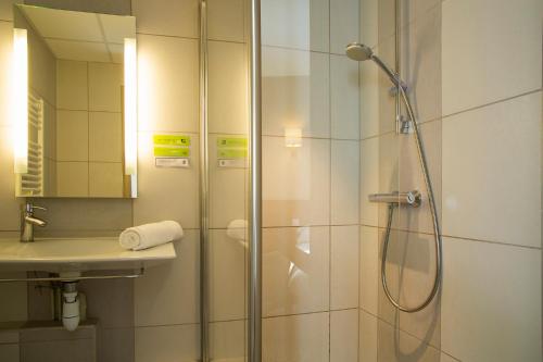 ein Bad mit einer Dusche und einem Waschbecken in der Unterkunft Park Hôtel & Appartements in Cholet