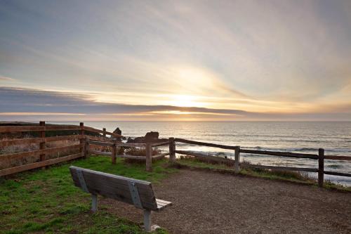 a bench sitting in front of the ocean at sunset at The Cliff House in Gualala