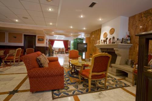 a living room with chairs and a table and a fireplace at Hotel Begoña Park in Gijón