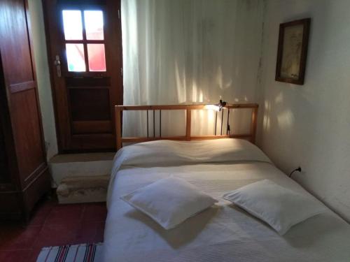 uma cama com duas almofadas num quarto com uma porta em Old Traditional House in the Castle of Monenvasia em Monemvasia