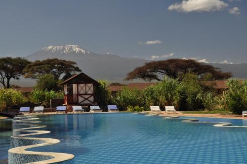a swimming pool with chairs and a mountain in the background at Kilima Safari Camp in Amboseli
