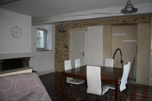 a dining room with a wooden table and white chairs at Les Mistinguettes in Pouzauges