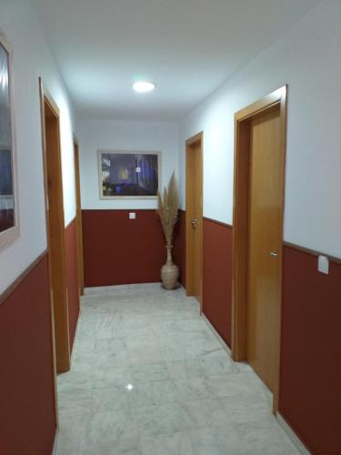 un couloir avec deux portes et un vase dans l'établissement Hostal Monteluna, à Rociana