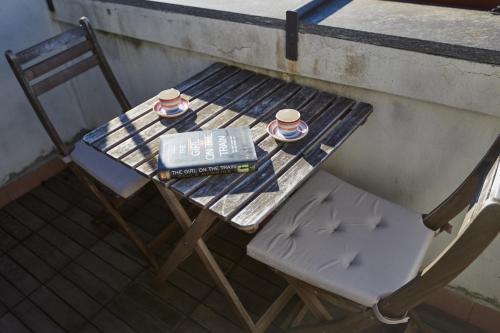 una mesa y una silla con un libro y dos tazas en Sempione Cozy Studio, en Milán