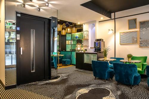 a room with blue chairs and a table and a kitchen at Hotel Pilime in Paris