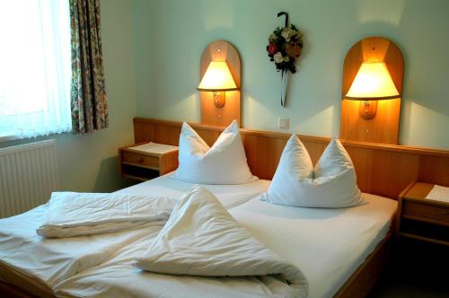 a bedroom with two beds with white sheets and pillows at Ferienwohnungen am See in Obertrum am See