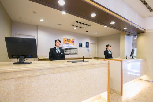 two women are standing behind a counter in a lobby at Shimane Hamada Washington Hotel Plaza in Hamada