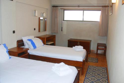 コスタ・ダ・カパリカにあるTubarinho Apartmentのベッド2台と窓が備わるホテルルームです。